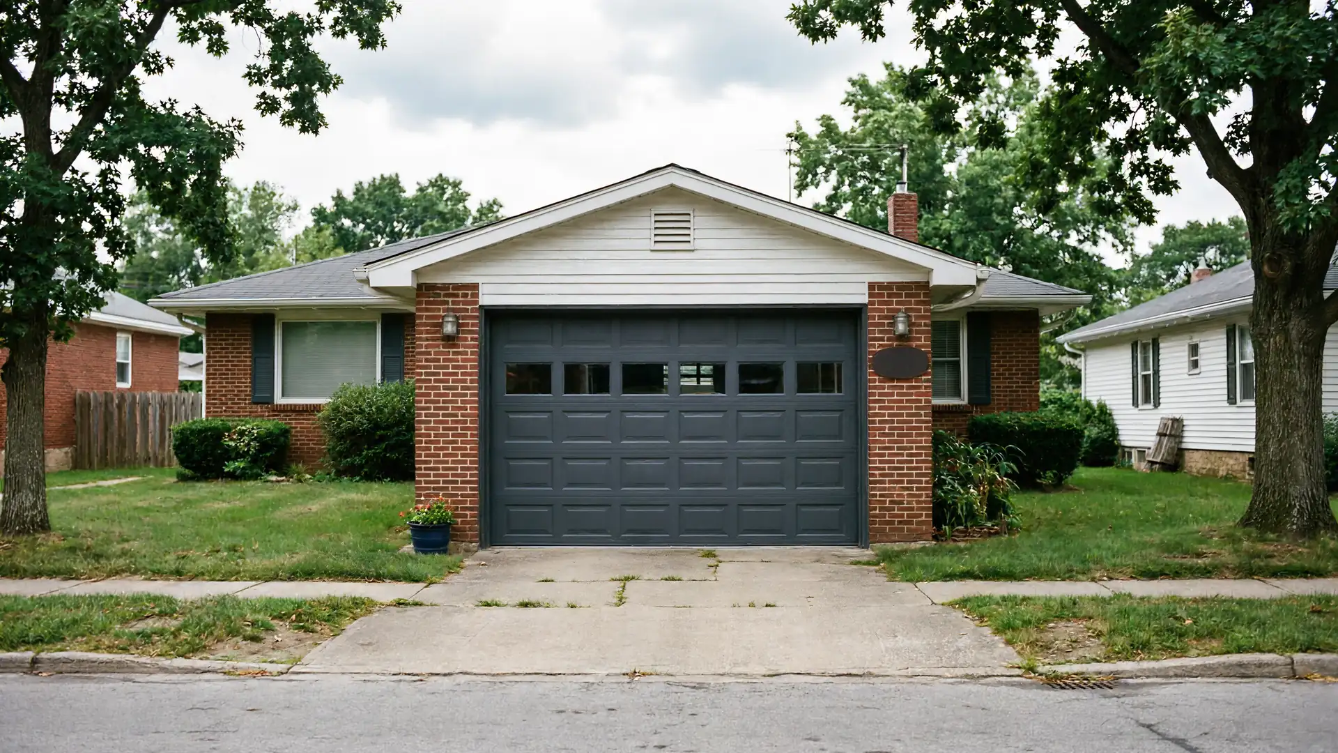 A gray garage door is on a brick house with a white gable.